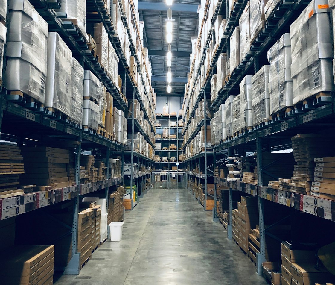 Entorno logístico profesional con estanterías industriales, palés, cajas y mercancía organizada para distribución comercial